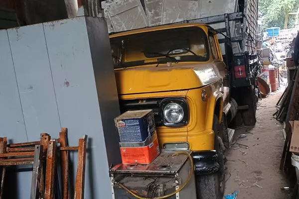 Caminhão amarelo da Lapa carregado com chapas metálicas dentro do galpão