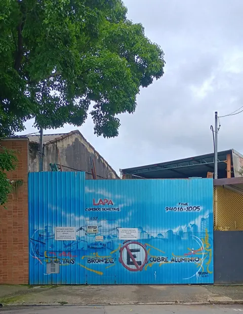 Portão azul pintado com o nome Lapa Comércio de Metais e os metais bronze, cobre e alumínio